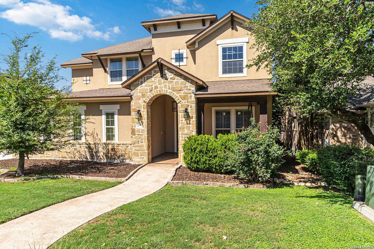 The arched front entry of 28722 Front Gate framed by limestone columns, with the walkway leading from the curb to the wood front door