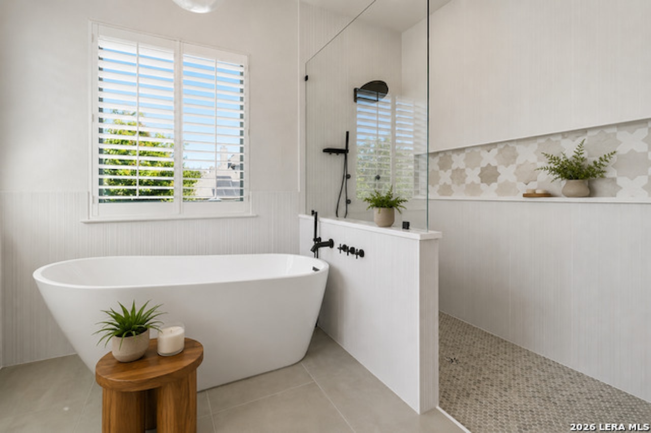 Spa-inspired primary bathroom at 28722 Front Gate with a freestanding soaking tub, a glass walk-in shower with a star-pattern tile niche, and plantation shutters