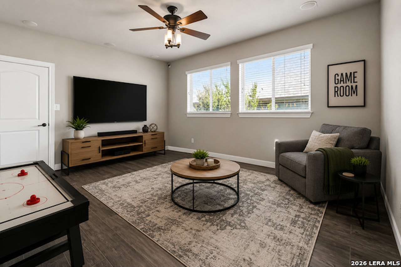 Game room at 28722 Front Gate with an air hockey table, a wall-mounted television on a wood console, a gray lounge chair, and a framed GAME ROOM print