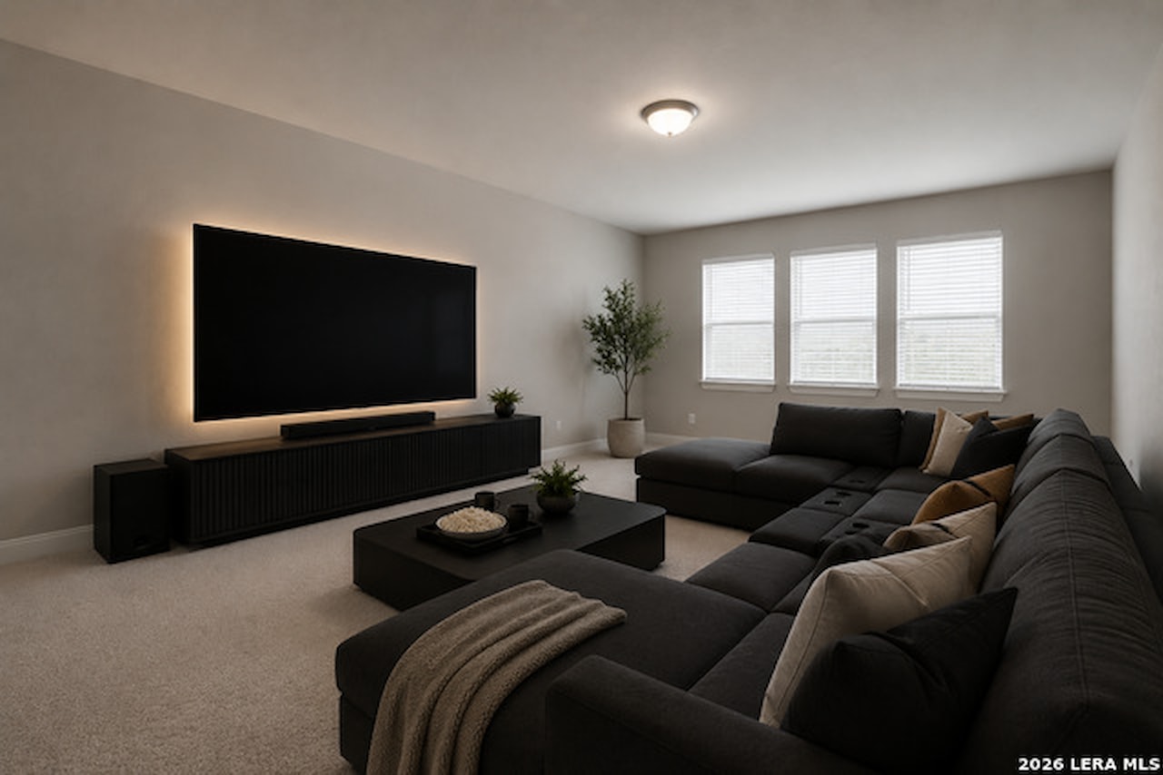 Media room at 28722 Front Gate with a large back-lit wall-mounted television, a dark sectional sofa, carpet, and a row of windows with blinds